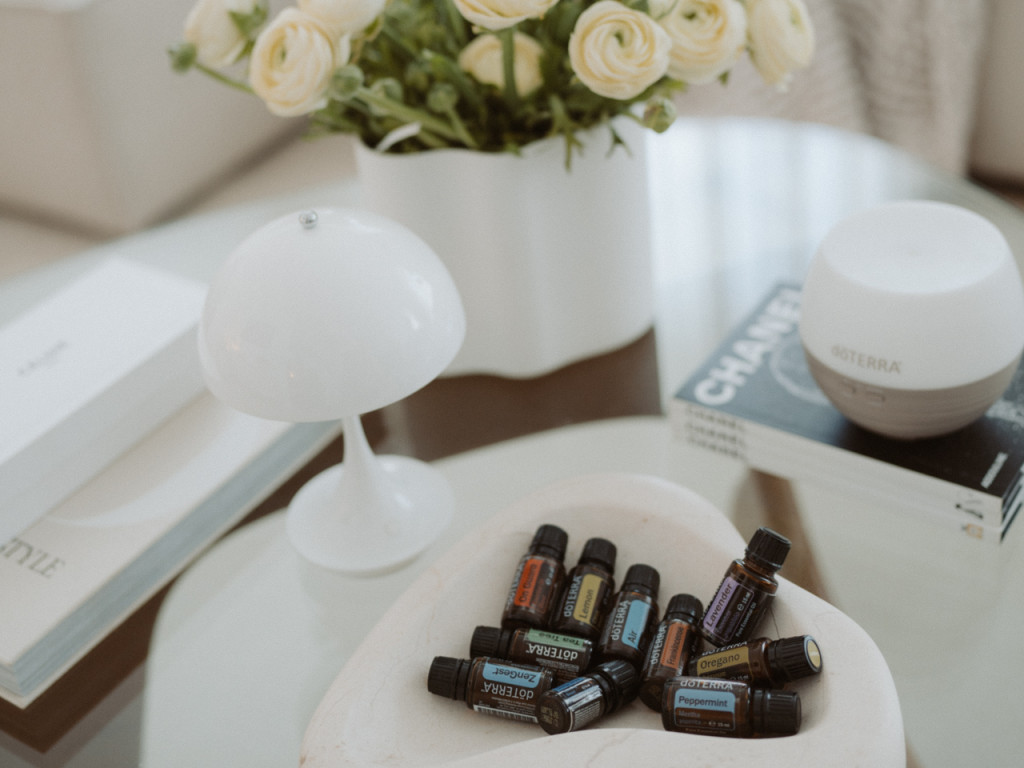 10 ätherische Öle aus dem doTERRA Home Essentials Kit in dekorativer Schale, Diffuser und ein schöner Blumenstrauß auf einem Tisch