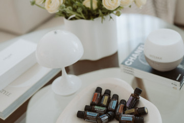 10 ätherische Öle aus dem doTERRA Home Essentials Kit in dekorativer Schale, Diffuser und ein schöner Blumenstrauß auf einem Tisch